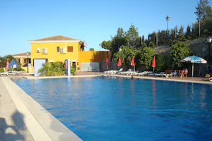 Camping Presa La Viňuela - Swimmingpool mit einem Gebäude des Campingplatzes im Hintergrund