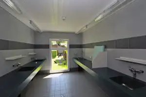 Camping-Küchenzeile mit zwei Spülen, Arbeitsplatten und offenem Zugang zum Außenbereich mit Gartenblick.