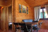 Camping Puerta de la Demanda - Hauptzimmer eines Holzbungalows mit Tisch und Stühlen