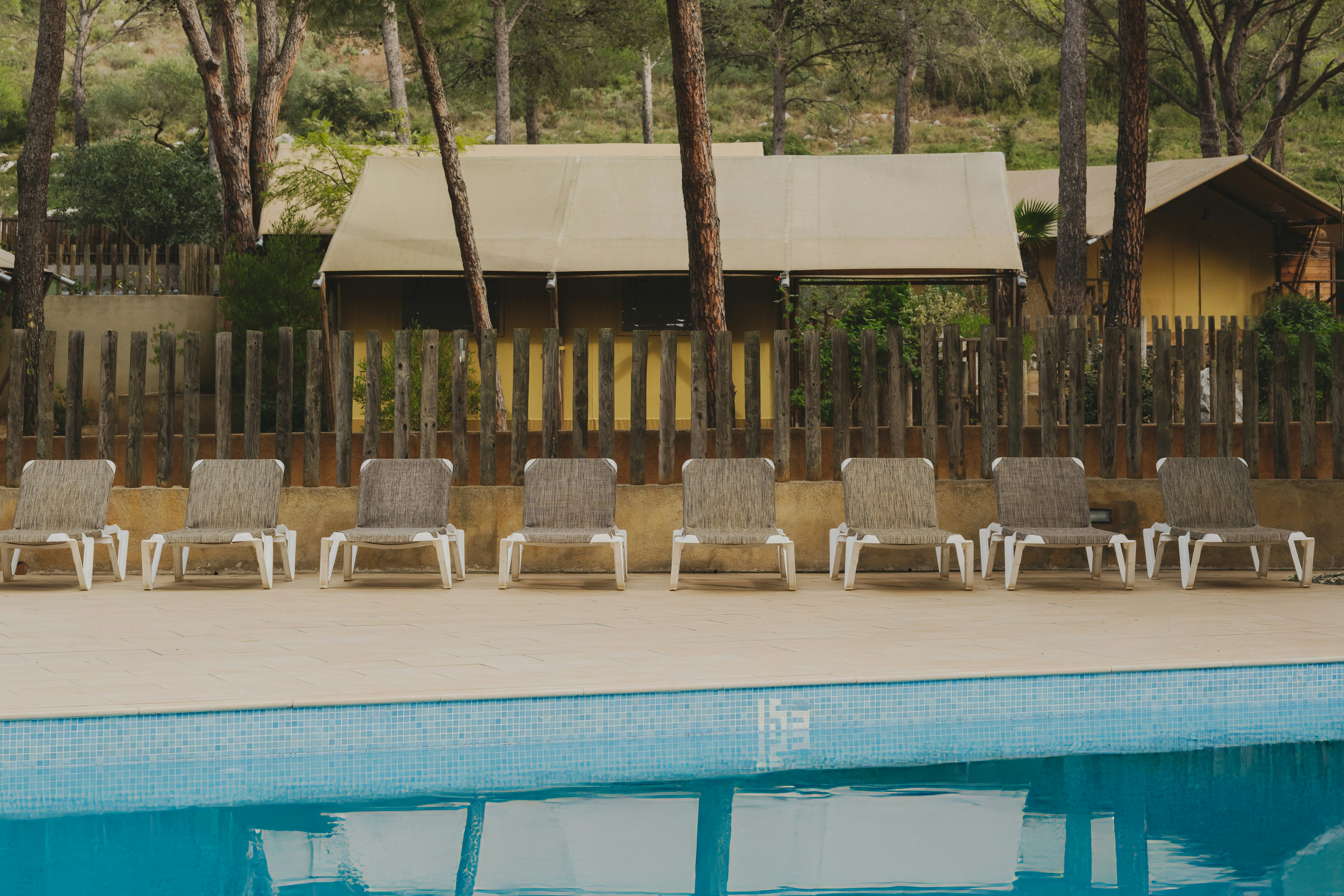 wecamp l'Escala Punta Milá - Blick auf den Pool mit Liegestühlen und Mietunterkünften im Hintergrund