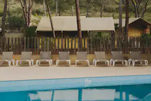 wecamp l'Escala Punta Milá - Blick auf den Pool mit Liegestühlen und Mietunterkünften im Hintergrund