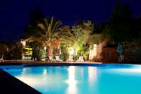 Camping Quinta das Cegonhas - Der Swimmingpool am Abend mit Liegestühlen unter Palmen