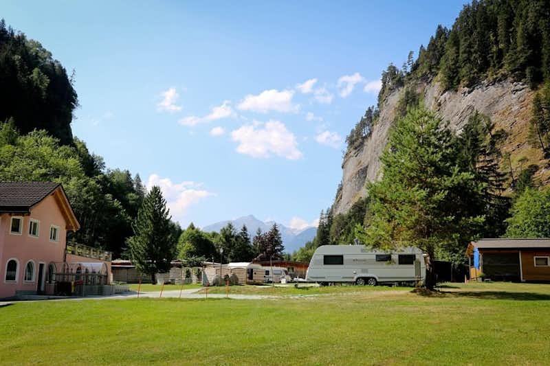 Camping Rania - der Campingplatz mit Hauptgebäude, einem Wohnwagen und Bergen im Hintergrund