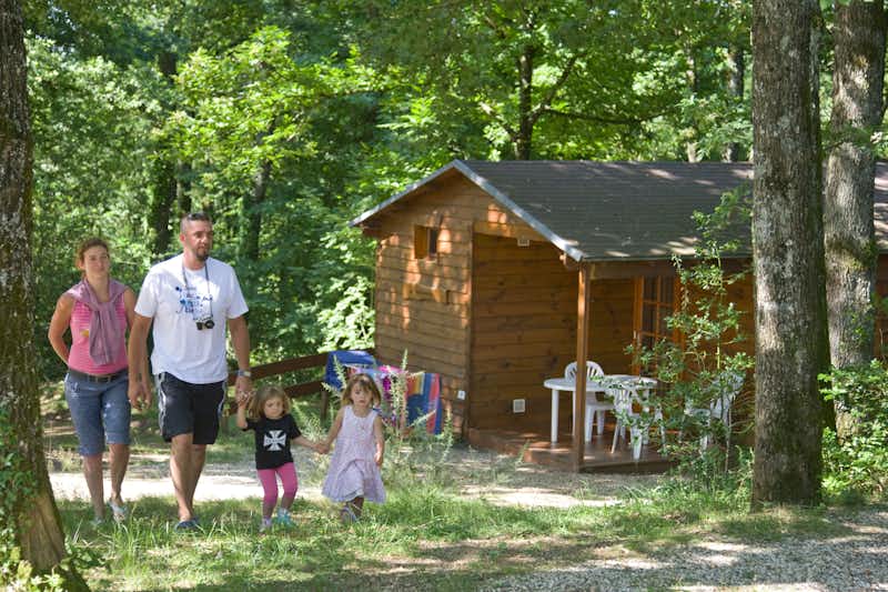 Camping Relais de l' Entre 2 Lacs - Holzhütte mit überdachter Veranda und Sitzgelegenheiten mit Familie im Vordergrund
