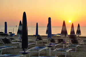 Camping Residence Don Antonio - Liegestühlen und Sonnenschirmen am Strand mit Blick auf das Meer bei Sonnenuntergang