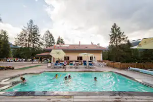 Camping & Resort Fiemme Village - Poolbereich vom Campingplatz mit Liegestühlen und Sonnenschirmen, Restaurant mit Terrasse im Hintergrund