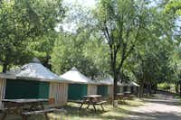 Camping Rio Vero - Mobilheime mit Picknicktischen vom Campingplatz zwischen Bäumen
