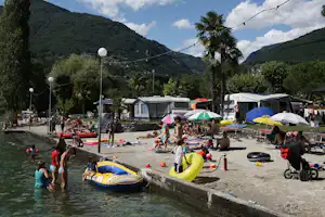 Camping Rivabella - Blick vom See Lago di Garlate auf den Strand und den Wohnwagen- und Zeltstellplatz vom Campingplatz