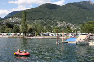 Camping Rivabella - Camper im Paddelboot, Wohnmobilstellplatz und Berge im Hintergrund