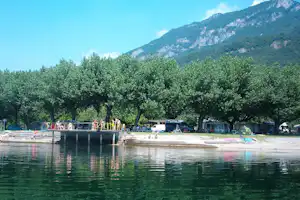 Camping Rivabella - Blick vom See auf den Campingplatz unter Bäumen