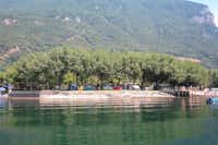 Camping Rivabella - Stellplätze unter Bäumen vom See aus fotografiert