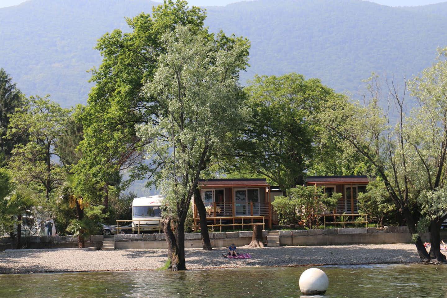 Camping Riviera - Blick auf Bungalows unter Bäumen und den Lago Maggiore 
