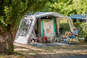 Campingzelt mit Vorzelt und Stühlen auf einem Stellplatz, im Hintergrund weitere Zelte und Bäume.