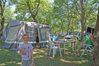 Camping Saint-Disdille - Familie sitzt vor ihrem Zelt unter Bäumen