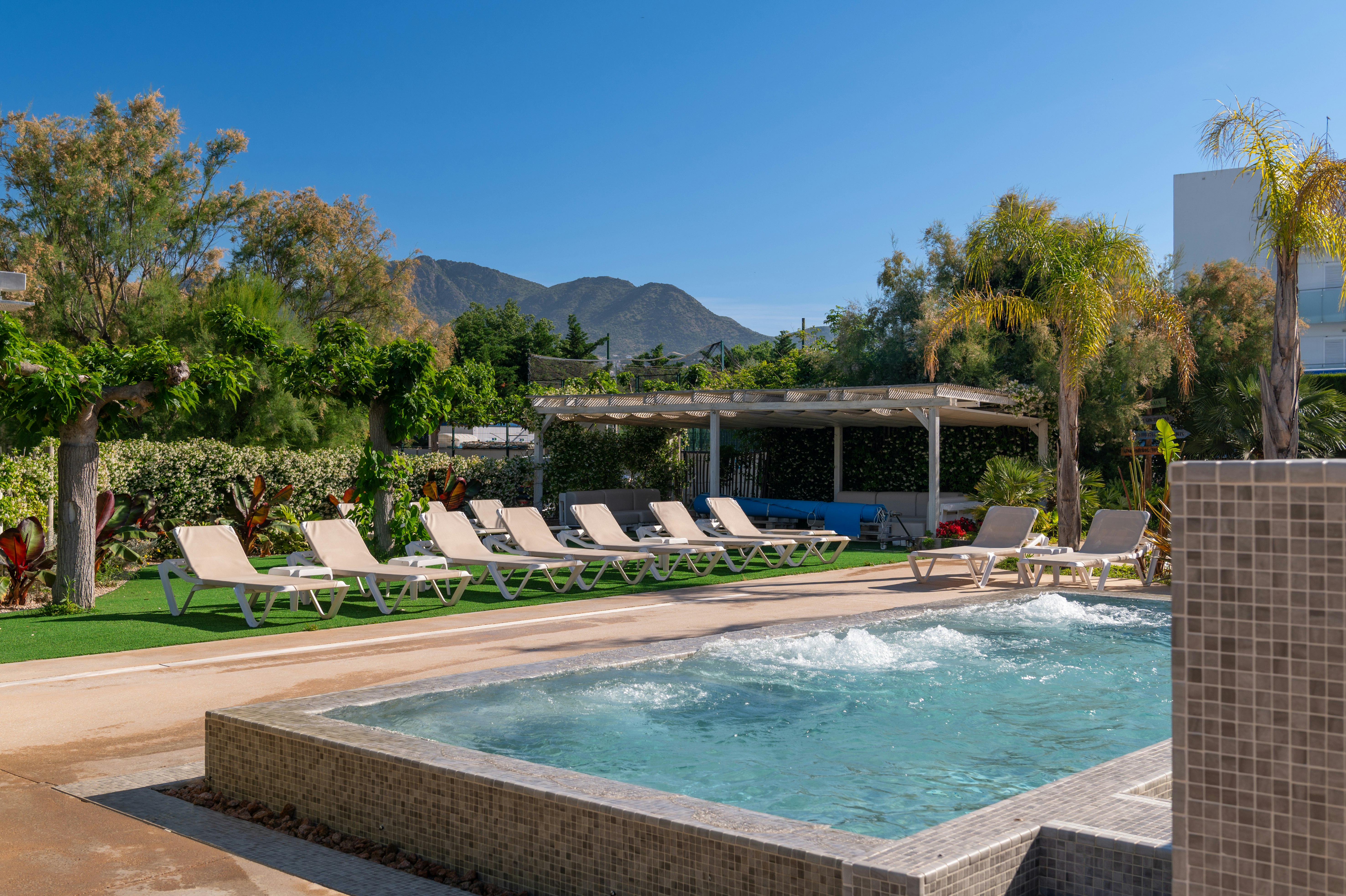 Beheizter Camping-Pool mit Liegen auf der Terrasse, umgeben von Bäumen und Blick auf die Berge im Hintergrund.