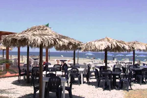Camping Salicamp - Strand vom Campingplatz mit Restaurant und Essbereich draußen im Vordergrund, Liegestühle und Sonnenschirme am Meer im Hintergrund
