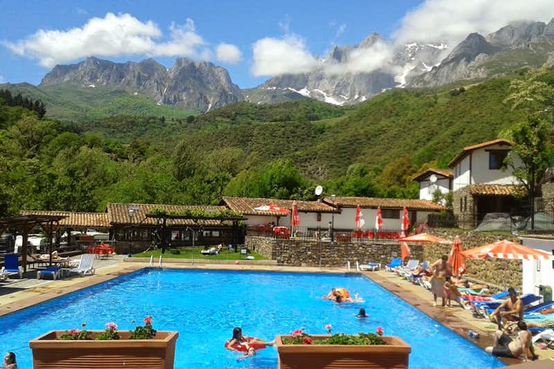 Camping San Pelayo  -  Pool vom Campingplatz mit Sonnenschirmen und Liegestühlen und Blick auf das Kantabrische Gebirge