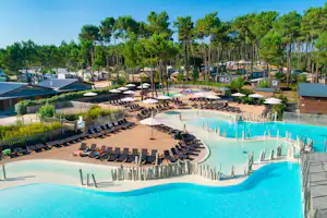 Großes Camping-Schwimmbecken mit Liegen und Sonnenschirmen, umgeben von Bäumen, Wegen und kleinen Gebäuden im Hintergrund.