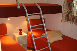 Innenansicht eines Wohnmobils mit Etagenbett, Leiter und Nachttisch neben den Betten.