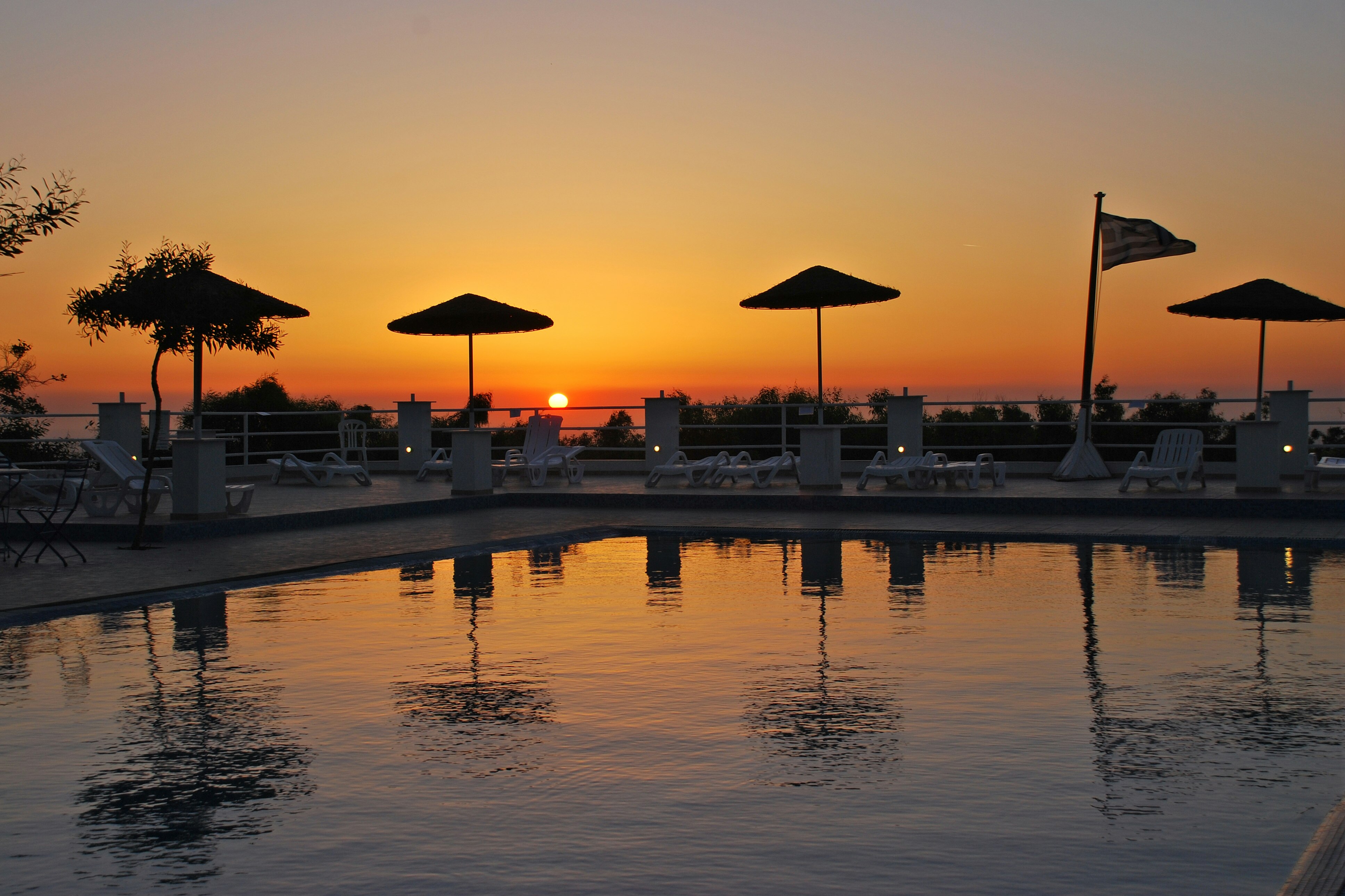 Camping Santoríni  -  Poolbereich vom Campingplatz mit Liegestühlen und Sonnenschirmen bei Sonnenuntergang