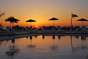 Camping Santoríni - Poolbereich vom Campingplatz mit Liegestühlen und Sonnenschirmen bei Sonnenuntergang
