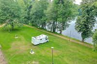 Camping Schloss Podewils - ein Wohnmobil auf auf den Stellplätzen auf der Wiese direkt am See