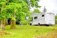 Camping Schloss Podewils - ein Wohnmobil auf einem Stellplatz auf der Wiese unter Bäumen