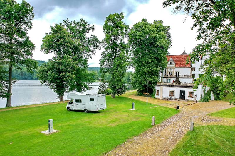 Camping Schloss Podewils - ein Wohnmobil auf einer Stellplatz-Wiese mit Blick auf den See
