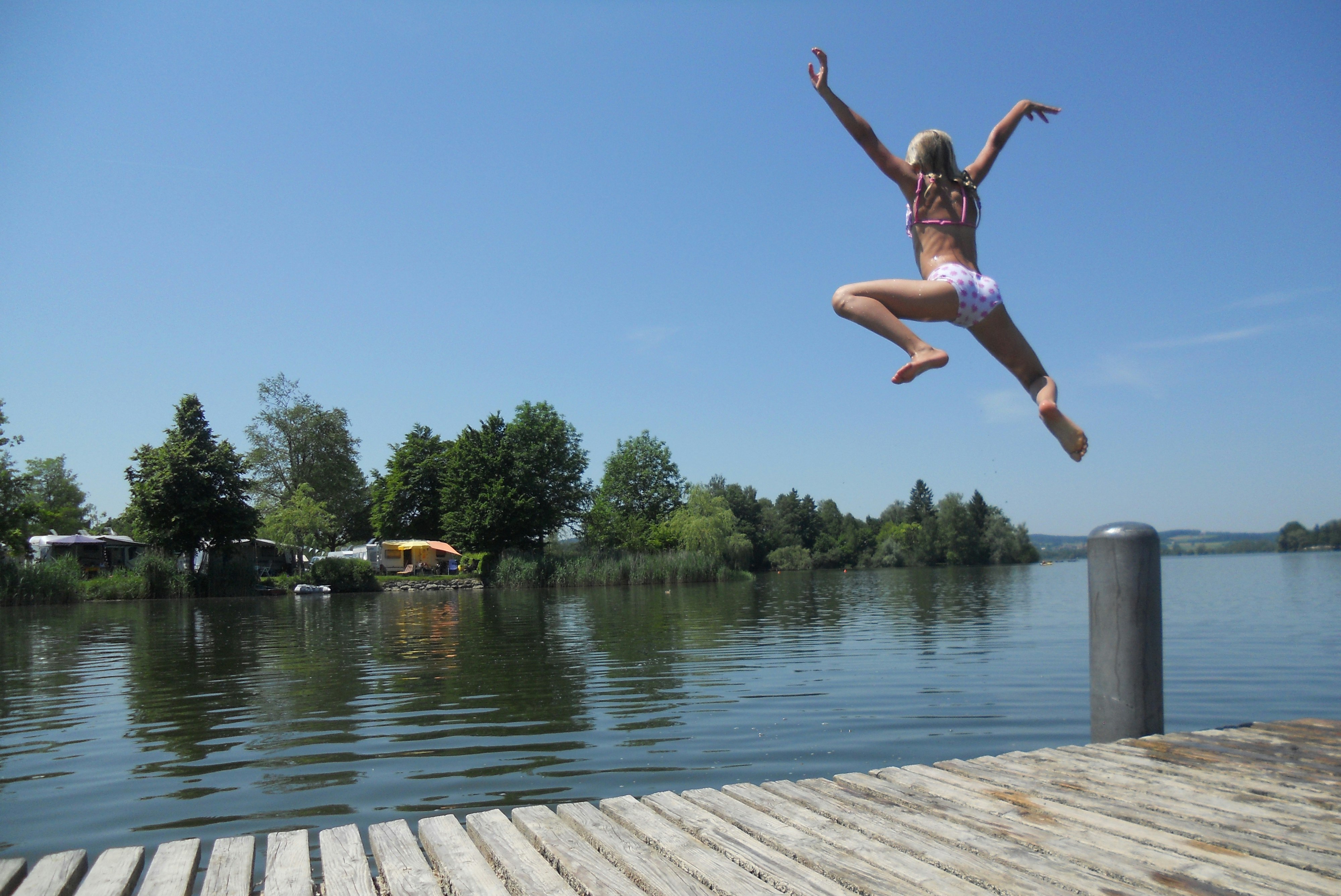 Camping Schwanenplatz - Camperin springt vom Badesteg in den See