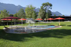 Camping Seefeld Park Sarnen - Wasserspielplatz vom Campingplatz mit Sonnenschirmen und Berglick