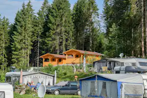 Camping Seespitze - Aufnahme der Wohnwagen- und Zeltstellplätze und Camping Bungalows vor einem Wald
