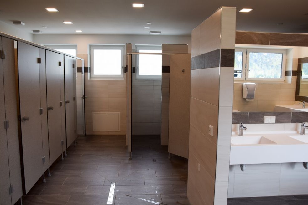 Camping Sennalpe - Innenraum des Sanitärgebäudes mit Waschbecken und Spiegeln, sowie Toilettenkabinen