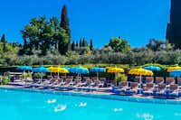 Camping Serenella - Gäste liegen am Pool in der Sonne  Pool vom Campingplatz mit LIegestühlen und Sonnenschirmen