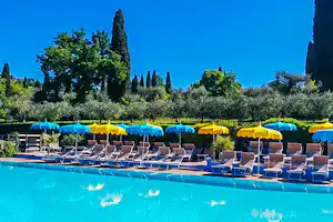 Camping Serenella - Gäste liegen am Pool in der Sonne Pool vom Campingplatz mit LIegestühlen und Sonnenschirmen