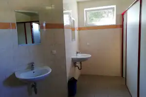 Camping-Badezimmer mit zwei Waschbecken, Fliesenwänden, Spiegeln und einem Fenster im Raum.