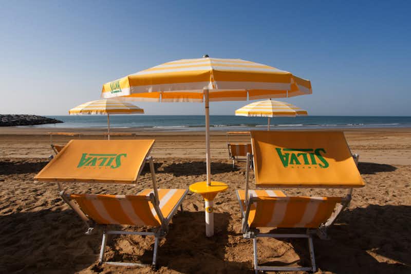 Camping Silva  -  Strand vom Campingplatz am Mittelmeer mit Sonnenschirmen und Liegestühlen