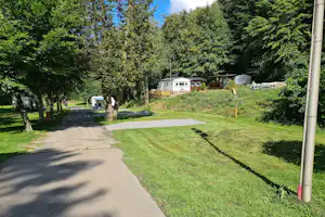 Camping Simmerschmelz Blick auf einen Standplatz mit gepflastertem Untergrund zum Abstellen sowie eine Rasenfläche