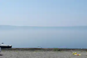 Blick auf den Strand mit Meer, Sanddünen und einem Boot am linken Bildrand.