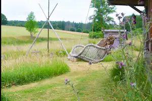 Hängematte am Campingplatz im grünen Gras, daneben ein Tipi-Zelt und ein Weg, im Hintergrund Wiese und Bäume.