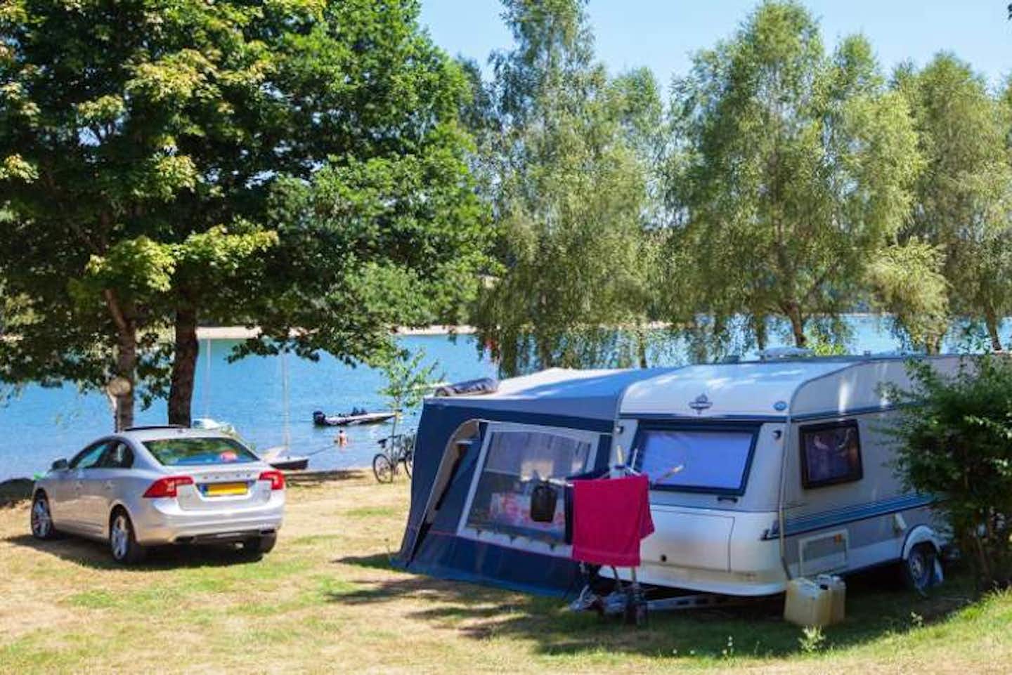 Camping Soleil Levant  -  Wohnwagen- und Zeltstellplatz vom Campingplatz auf grüner Wiese am Ufer des Sees