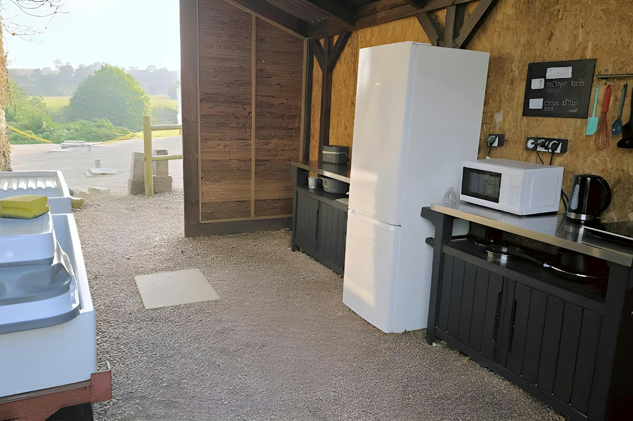 Camping Sous les étoiles Normandie - Gemeinschaftsküche mit Kochplatte, Kühlschrank und Geschirrspülbecken auf dem Campingplatz