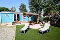 Camping & Spa CAP SOLEIL  -  Mobilheim mit Esstisch und Liegestühlen auf der Terrasse im Grünen