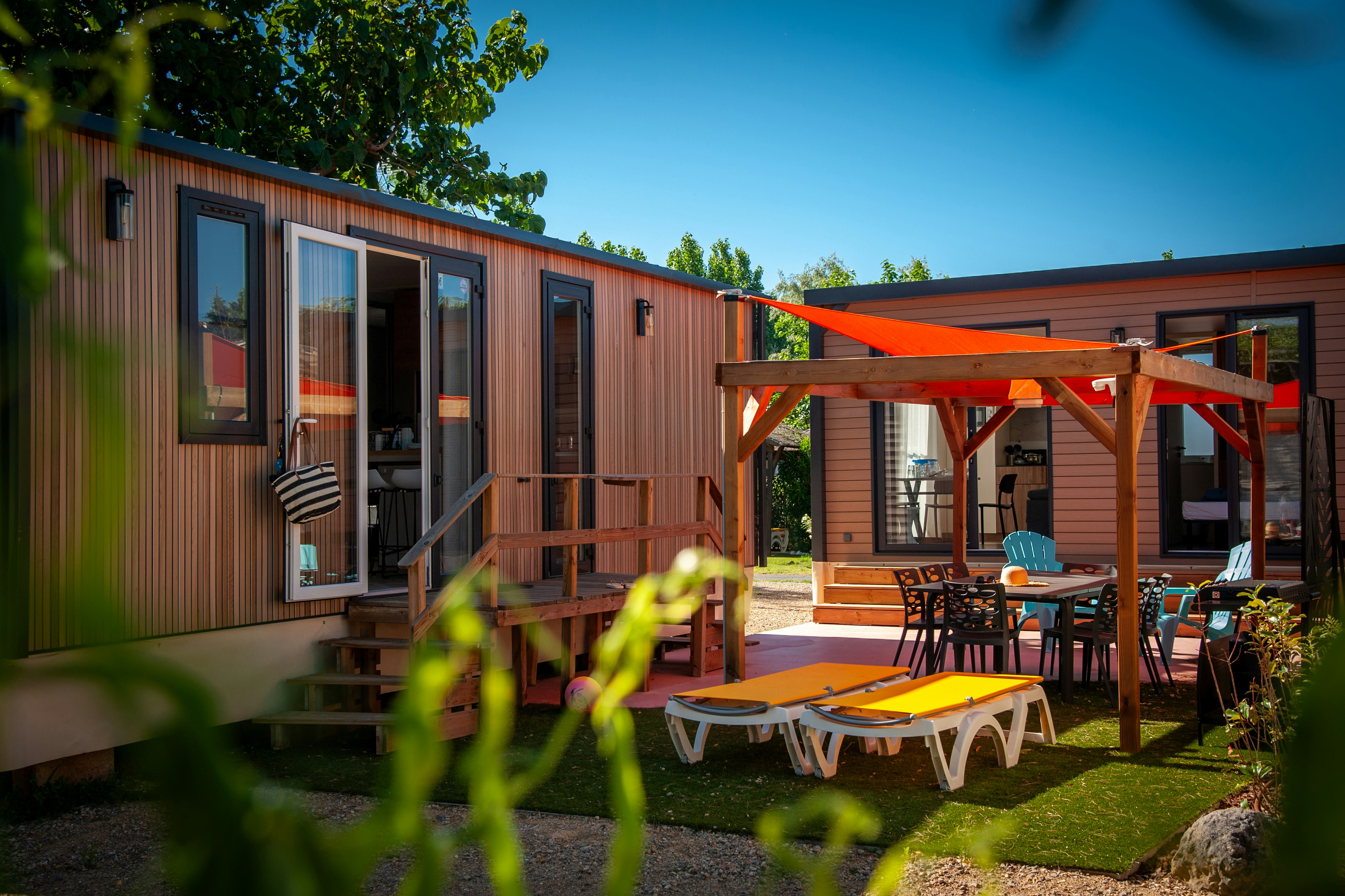 Camping & Spa CAP SOLEIL - Mobilheime Außenansciht mit Sonnensegel und Stühlen