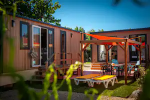 Camping & Spa CAP SOLEIL - Mobilheime Außenansciht mit Sonnensegel und Stühlen