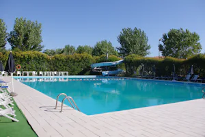 Camping Spinnaker - Pool vom Campingplatz mit Liegestühlen, Sonnenschirmen, Sitzmöglichkeiten und Wasserrutsche
