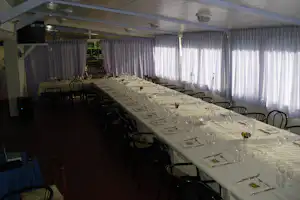 Festlich gedeckte Tafel mit Gläsern und Besteck im Zeltpavillon, weiße Vorhänge und Stühle am Tisch.