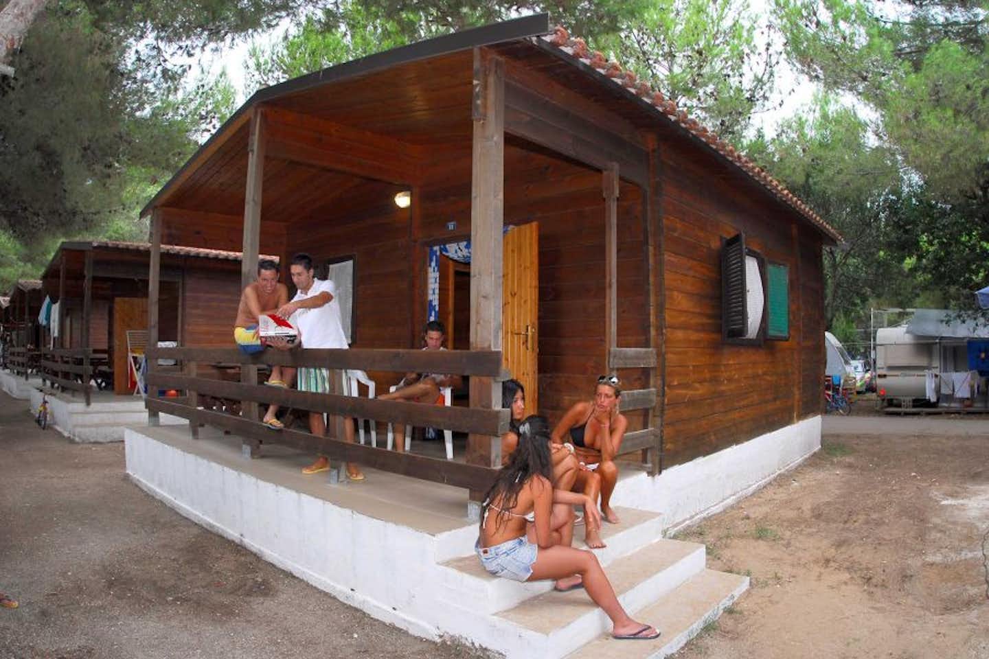 Camping Stella del Sud - Camper sitzen auf dem der Terrasse eines Holzbungalows auf dem Campingplatz