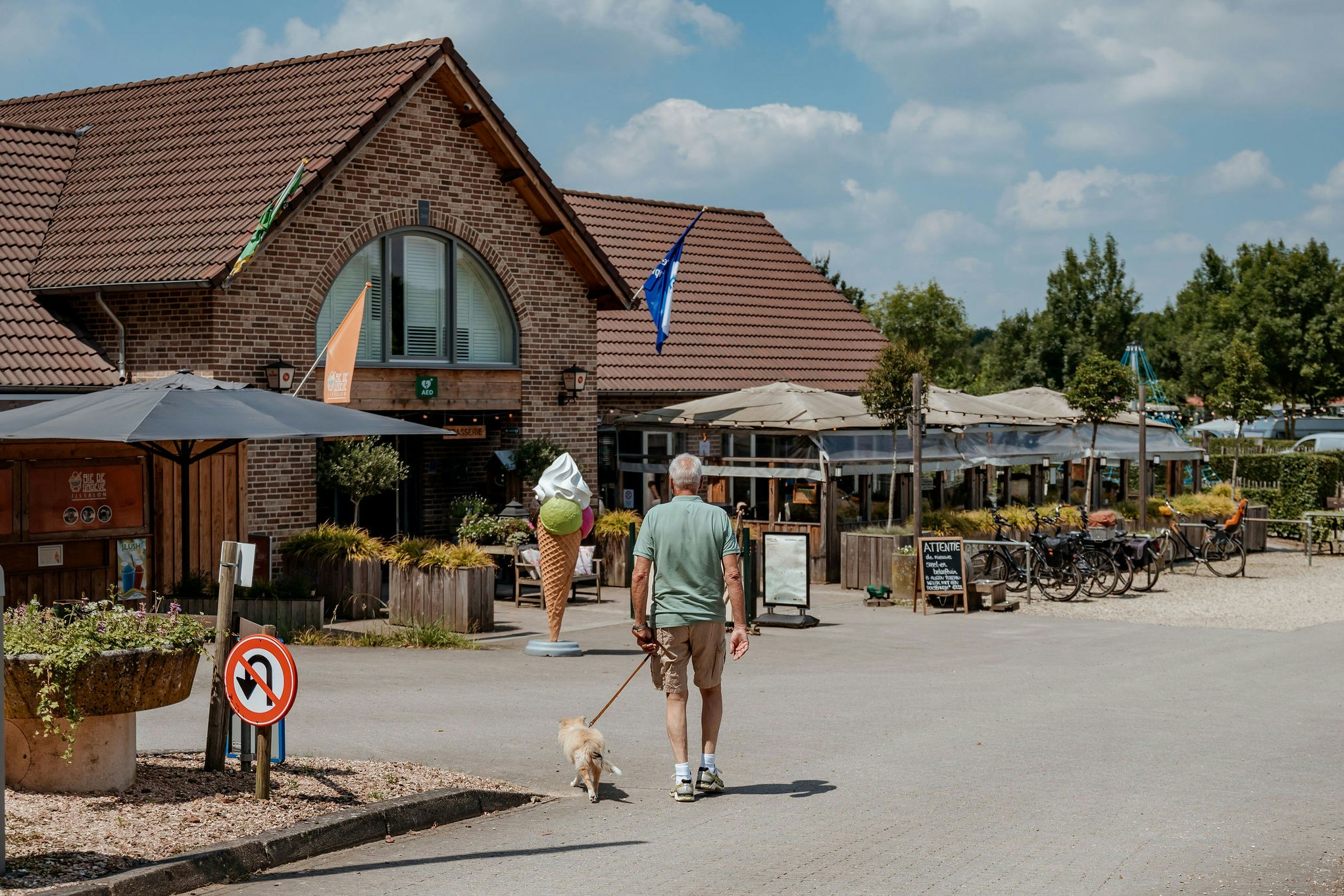 Ardoer Camping 't Geuldal - Camper mit Hund geht auf dem Campingplatz mit Restaurant und Terrasse spazieren