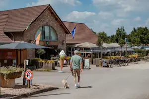 Ardoer Camping 't Geuldal - Camper mit Hund geht auf dem Campingplatz mit Restaurant und Terrasse spazieren