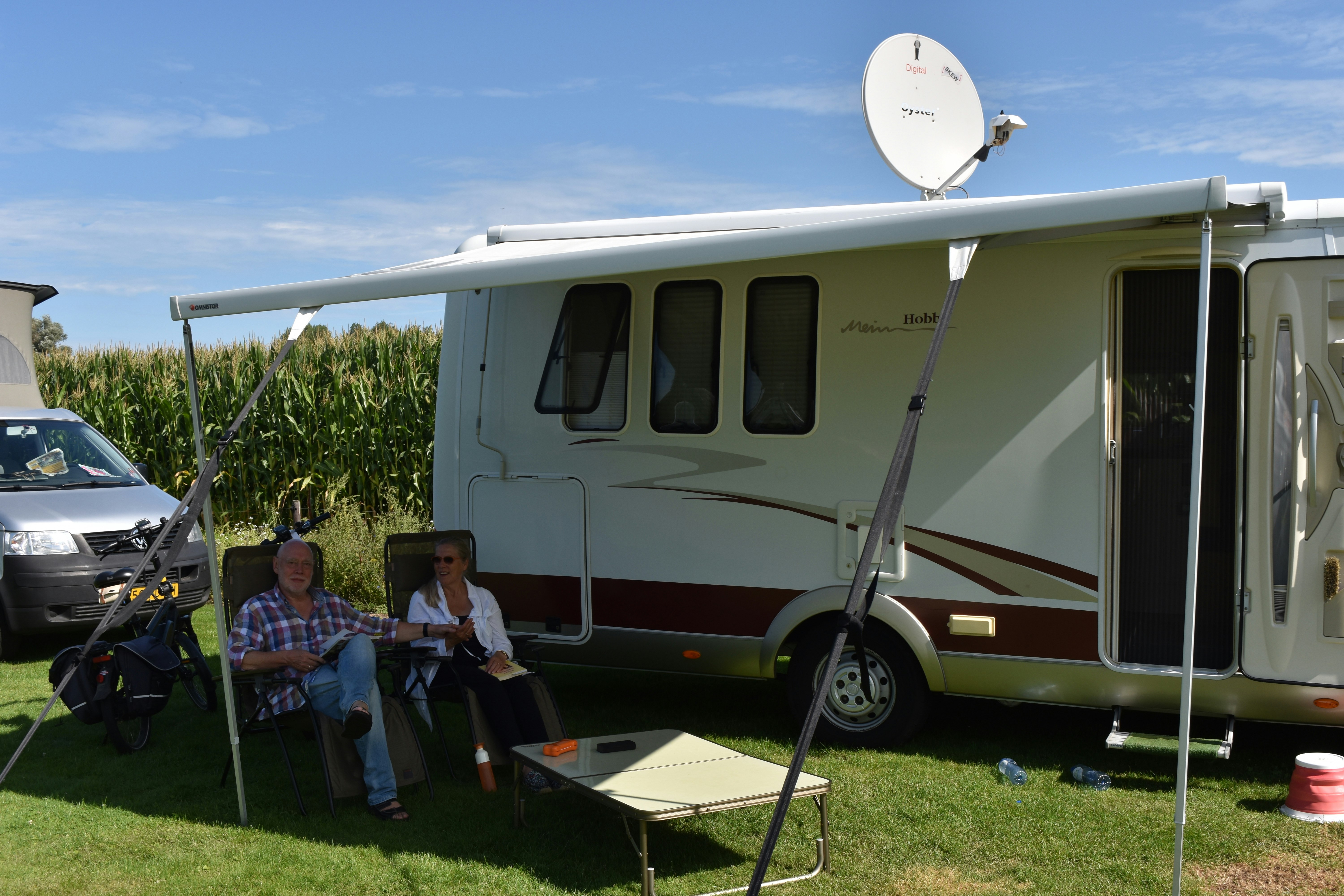 Camping 't Rouweelse Veld - Camper sitzen vor ihrem Wohnmobil auf einem Standplatz